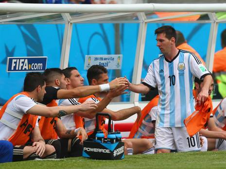 Messi dà la mano ai compagni in panchina dopo la sostituzione. Getty